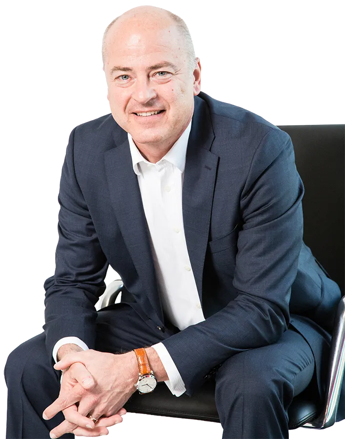 Andreas Kricsfalussy im blauen Anzug sitzt auf einem Stuhl und lächelt